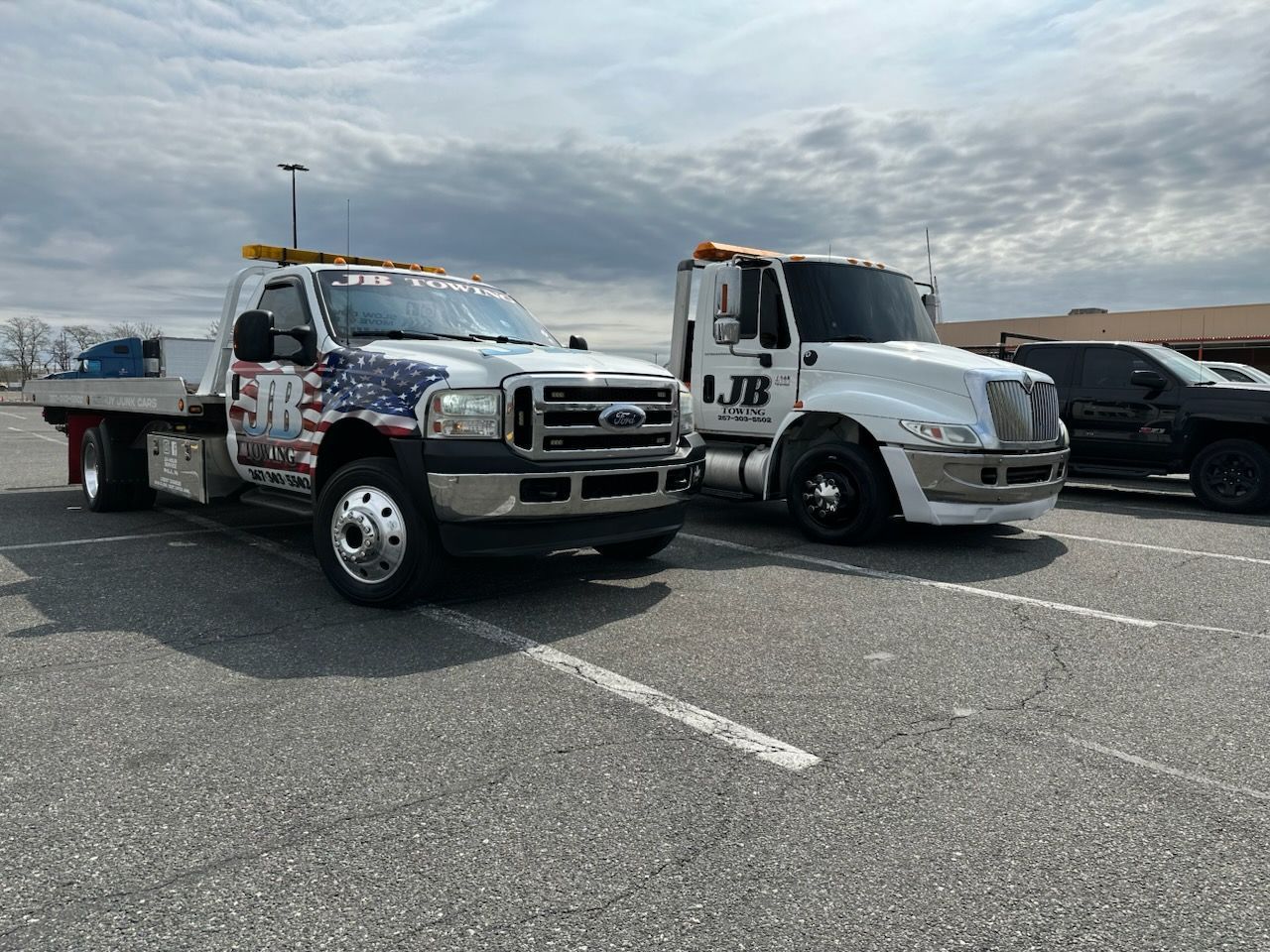 Two tow trucks are parked next to each other in a parking lot.