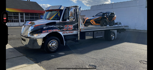 A tow truck is carrying a slingshot on the back of it.