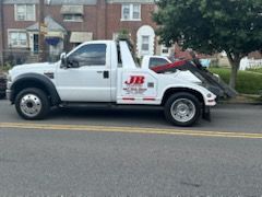 A white tow truck is parked on the side of the road.