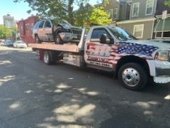 A tow truck with a car on the back is parked on the side of the road.