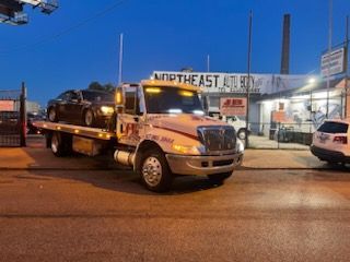 A tow truck with a car on the back is parked on the side of the road.
