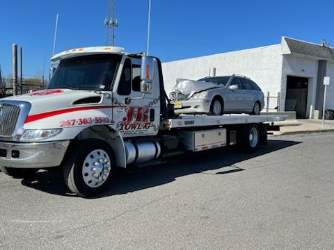 A tow truck with a car on the back is parked in front of a building.
