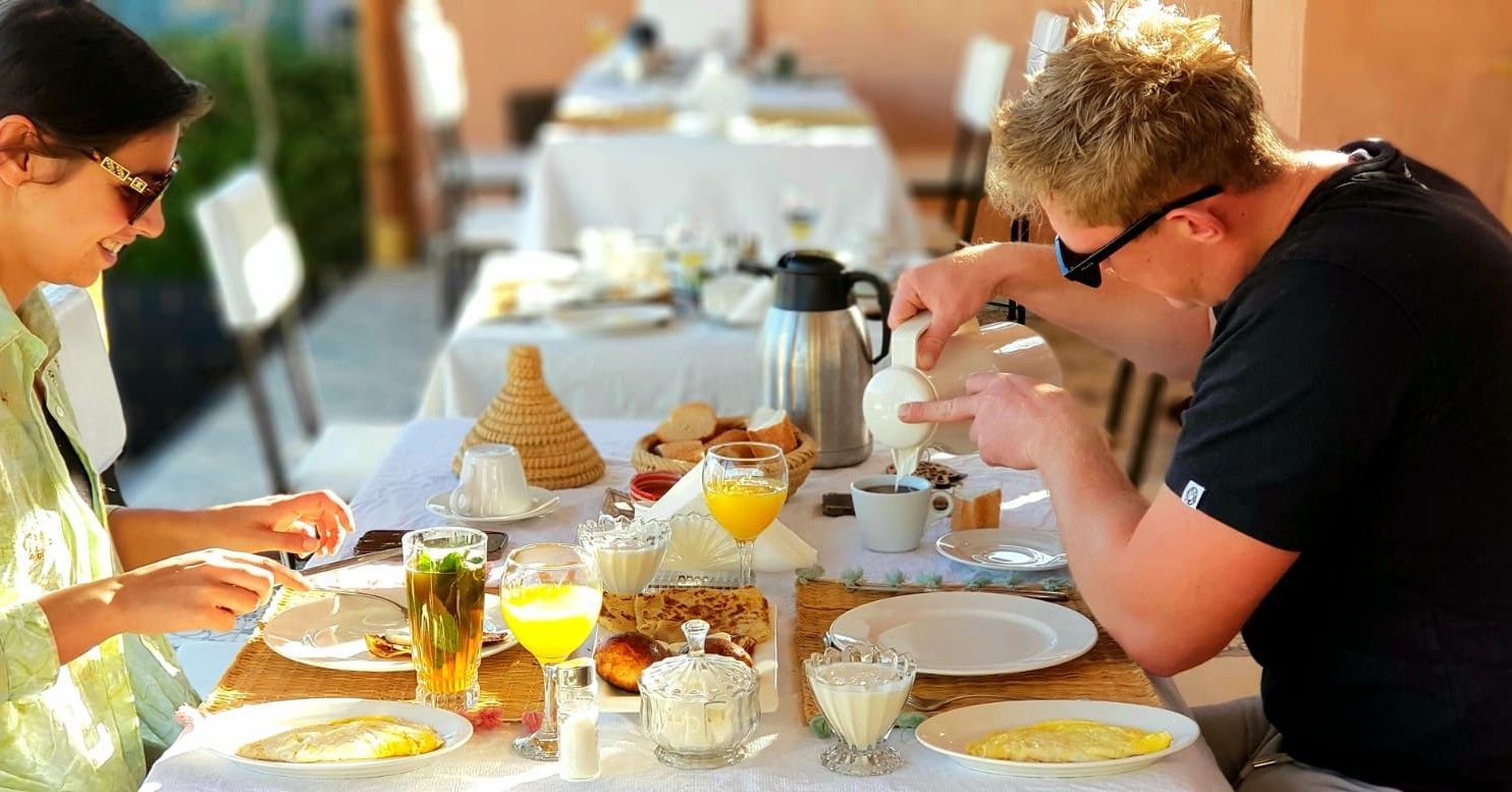 A man and a woman are sitting at a table eating food.
