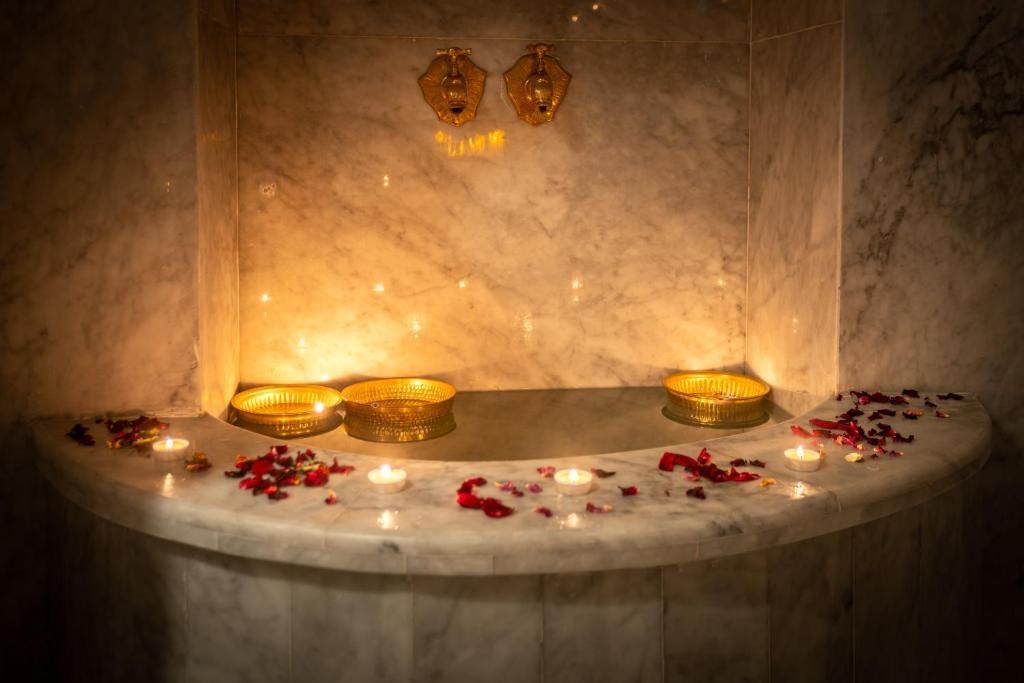 A bathroom with candles and rose petals on the counter.
