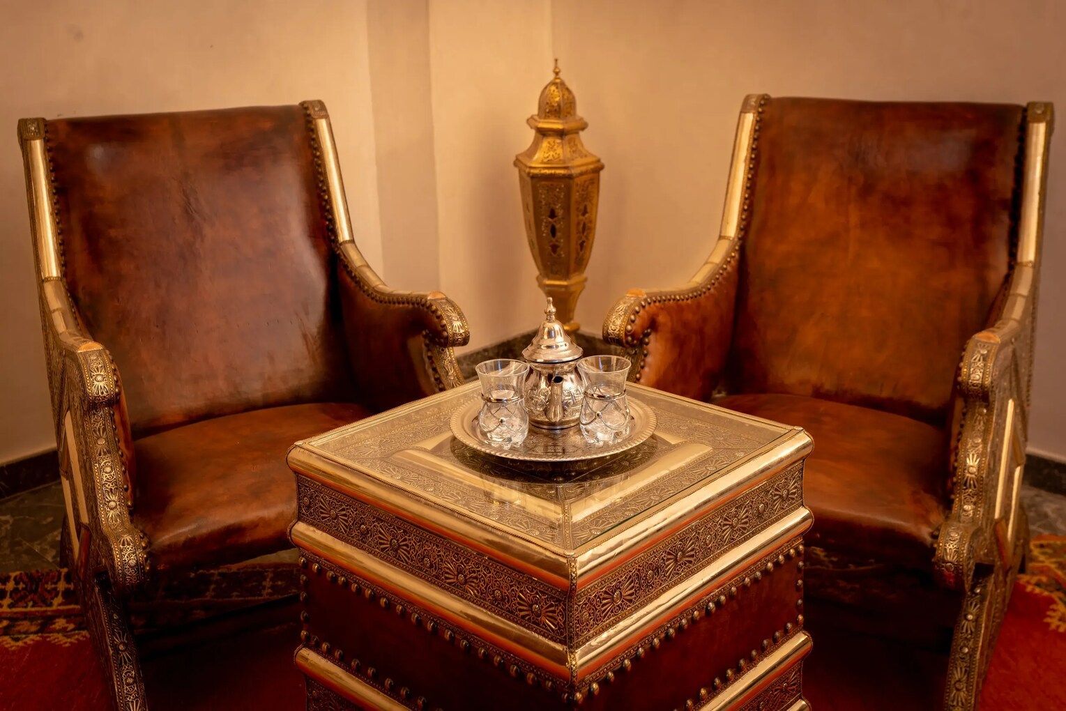 Two chairs are sitting next to a table with a tray of tea on it.