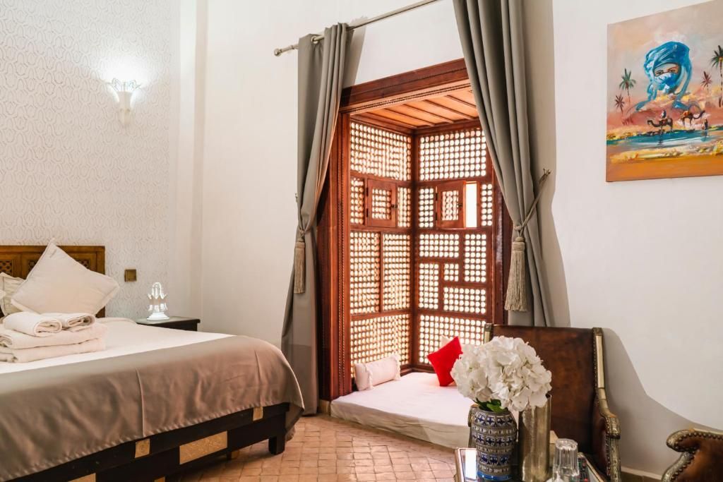 Bedroom with bed, ornate window, curtains, and artwork.