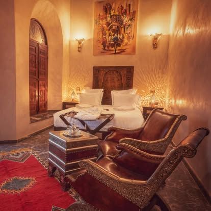 A bedroom with a bed , chairs , a table and a rug.