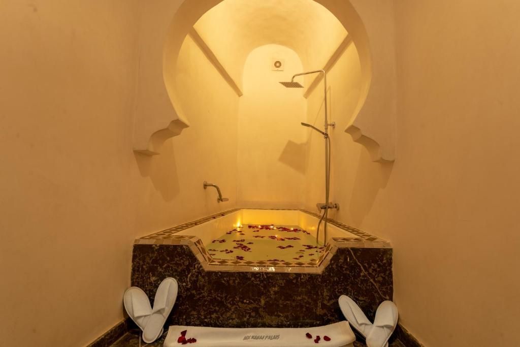 A bathroom with a bathtub filled with candles and towels.