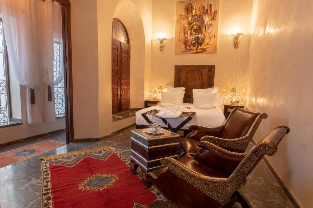 A bedroom with a bed , chairs , a table and a rug.