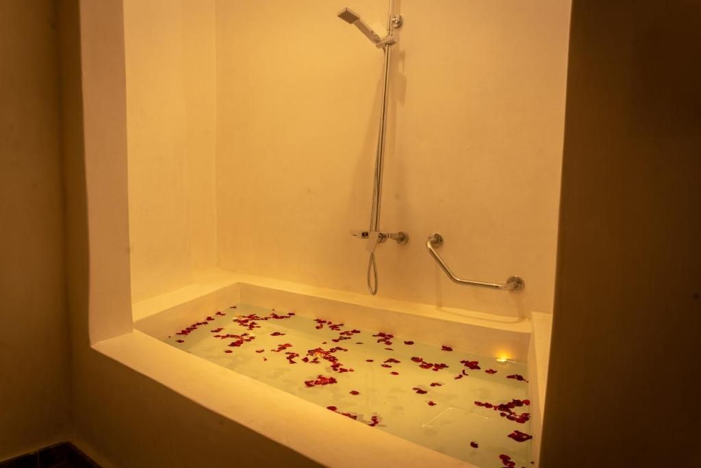 A bathtub filled with water and rose petals in a bathroom.