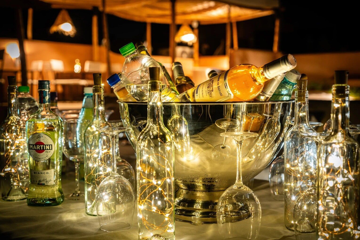 A table topped with bottles of alcohol and wine glasses.