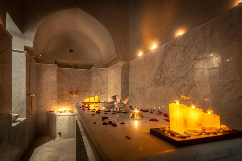 A bathroom with candles and rose petals on the counter.