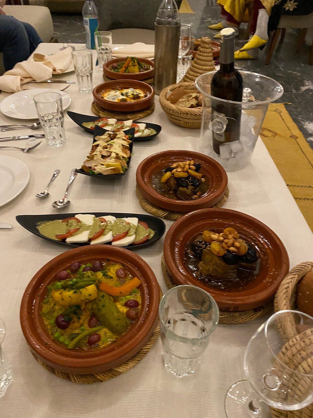 A table topped with plates of food and a bottle of wine.