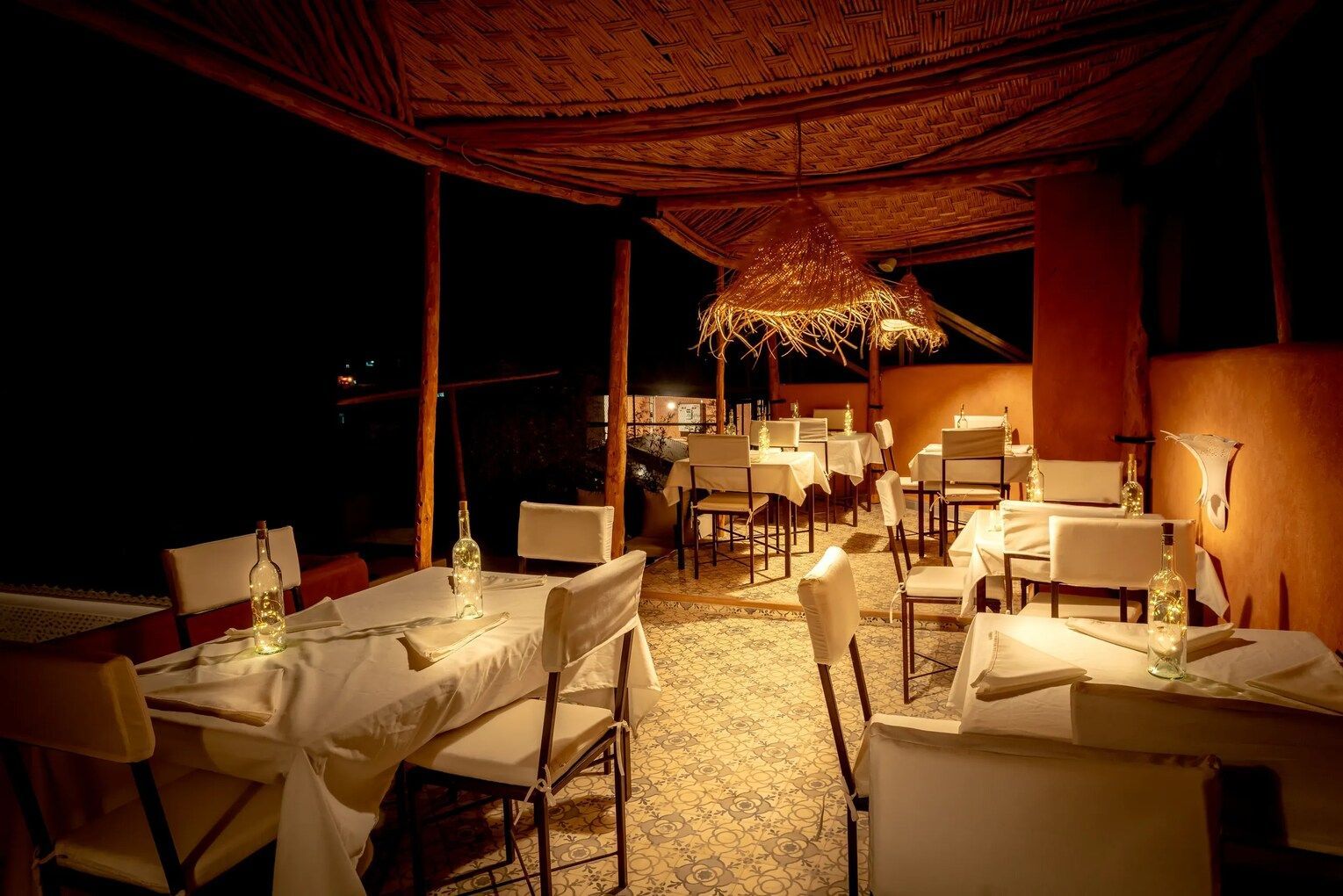 A restaurant with tables and chairs set up at night under umbrellas.