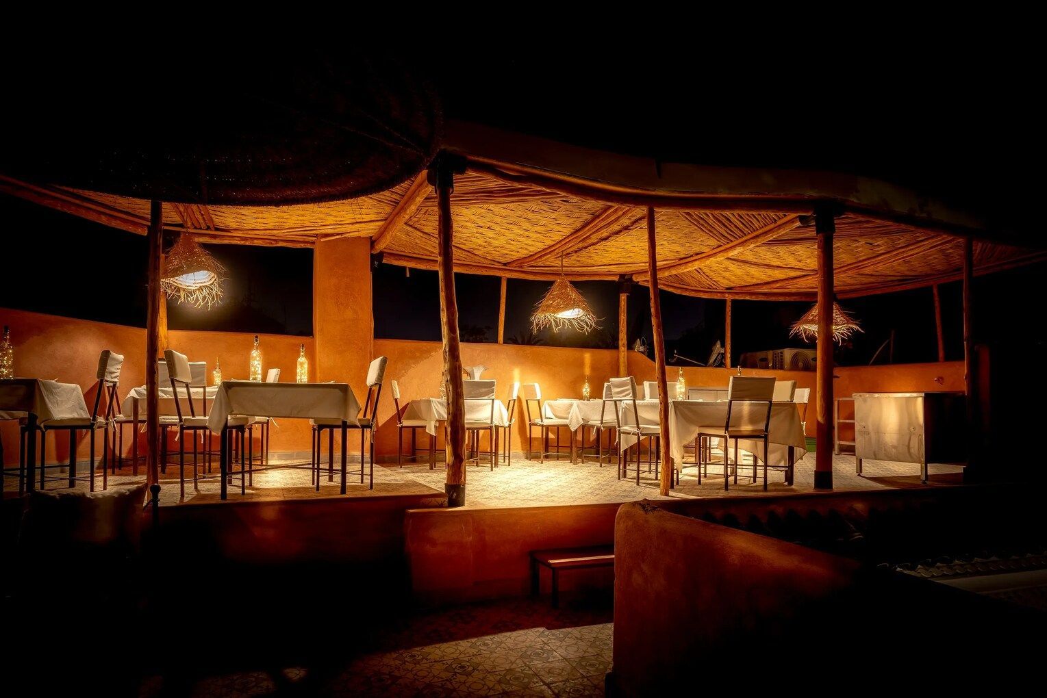 A restaurant with tables and chairs under a canopy at night.