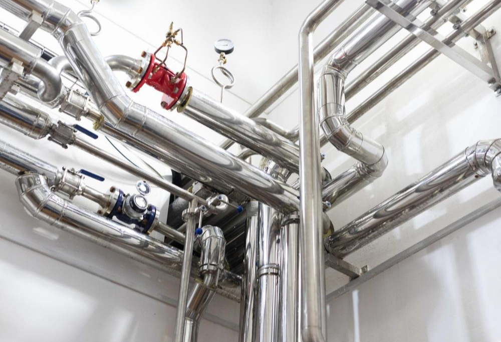 Shiny metal pipes and valves in an industrial setting.