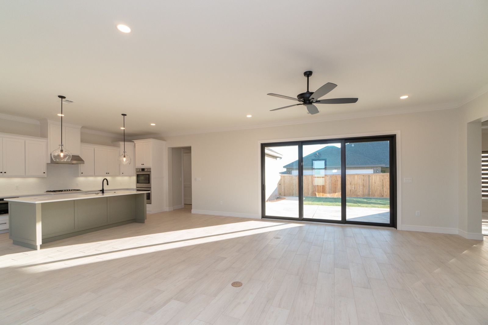 An empty kitchen with a ceiling fan and sliding glass doors