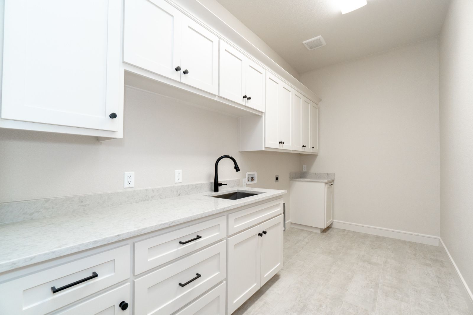 A kitchen with white cabinets and a sink.