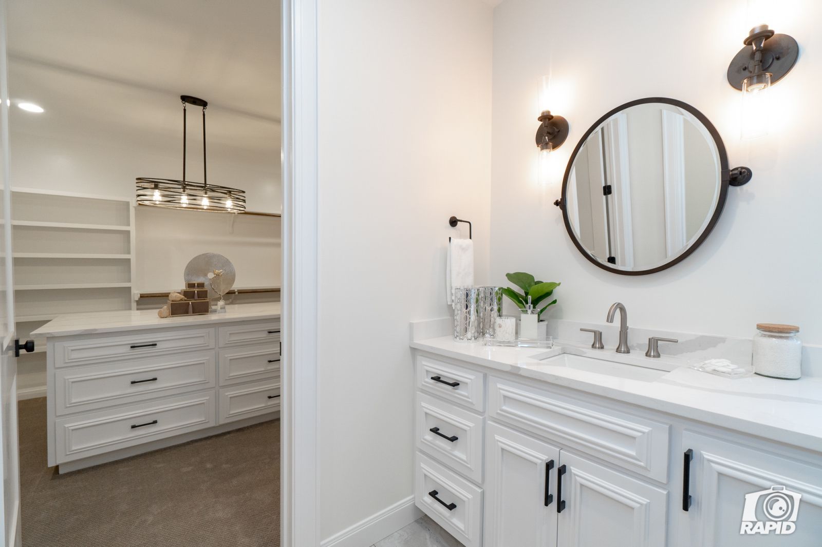 A bathroom with white cabinets and a round mirror