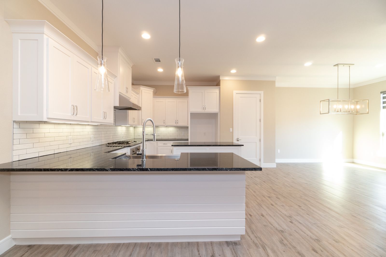 An empty kitchen with white cabinets and black counter tops