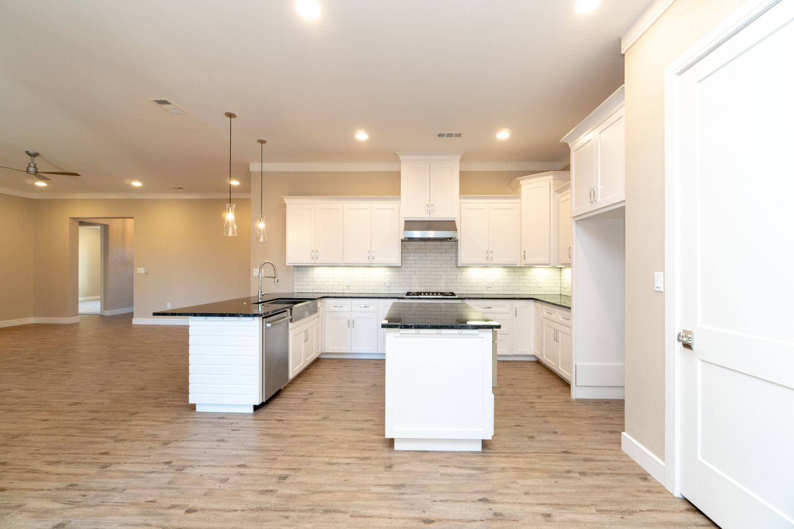 An empty kitchen with white cabinets and black counter tops