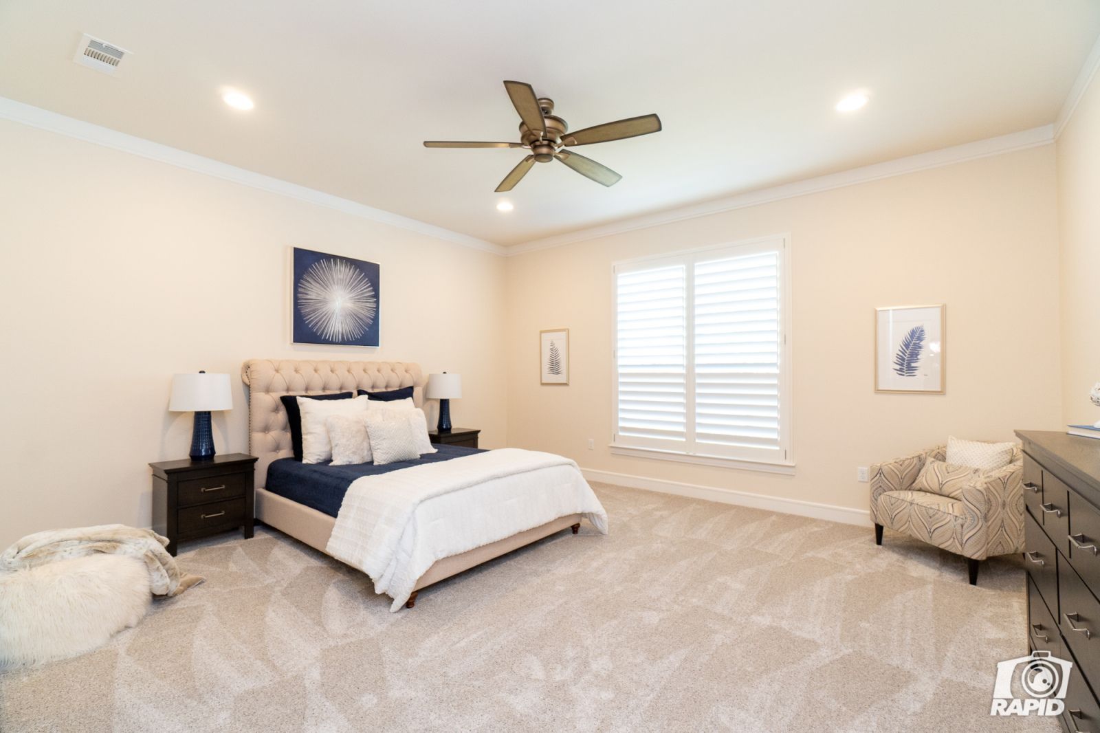 A bedroom with a large bed and a ceiling fan