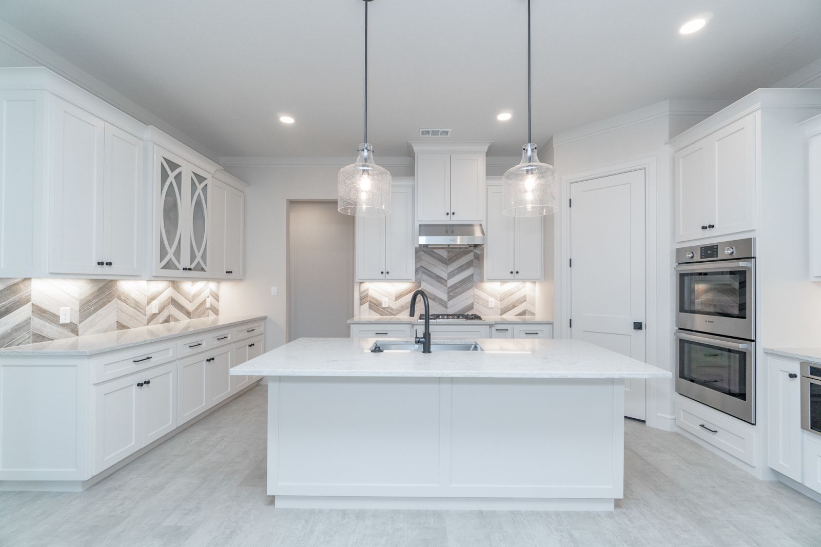 A kitchen with white cabinets and a large island in the middle.