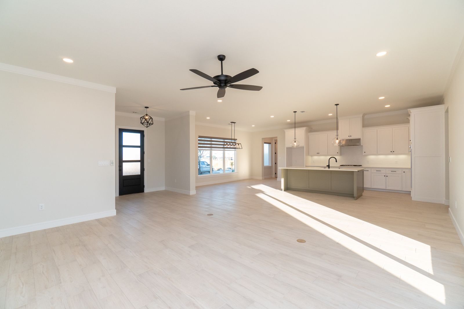 An empty room with a ceiling fan and a kitchen