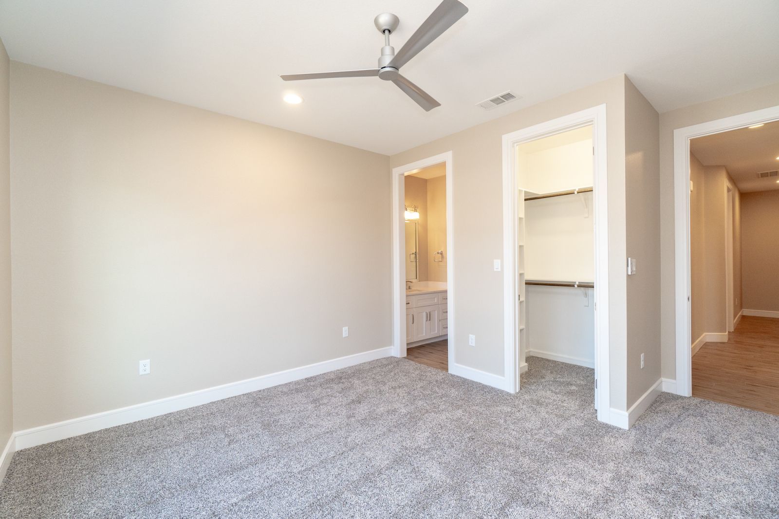 An empty bedroom with a ceiling fan and a walk in closet.