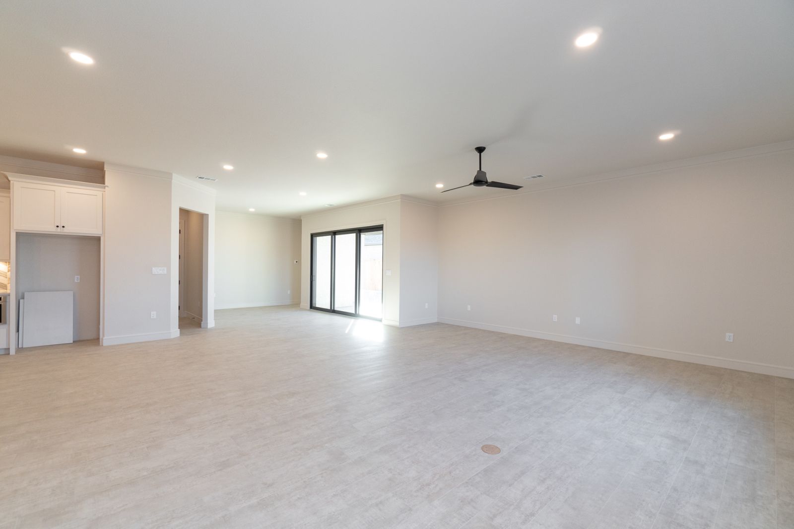 An empty room with a ceiling fan and sliding glass doors