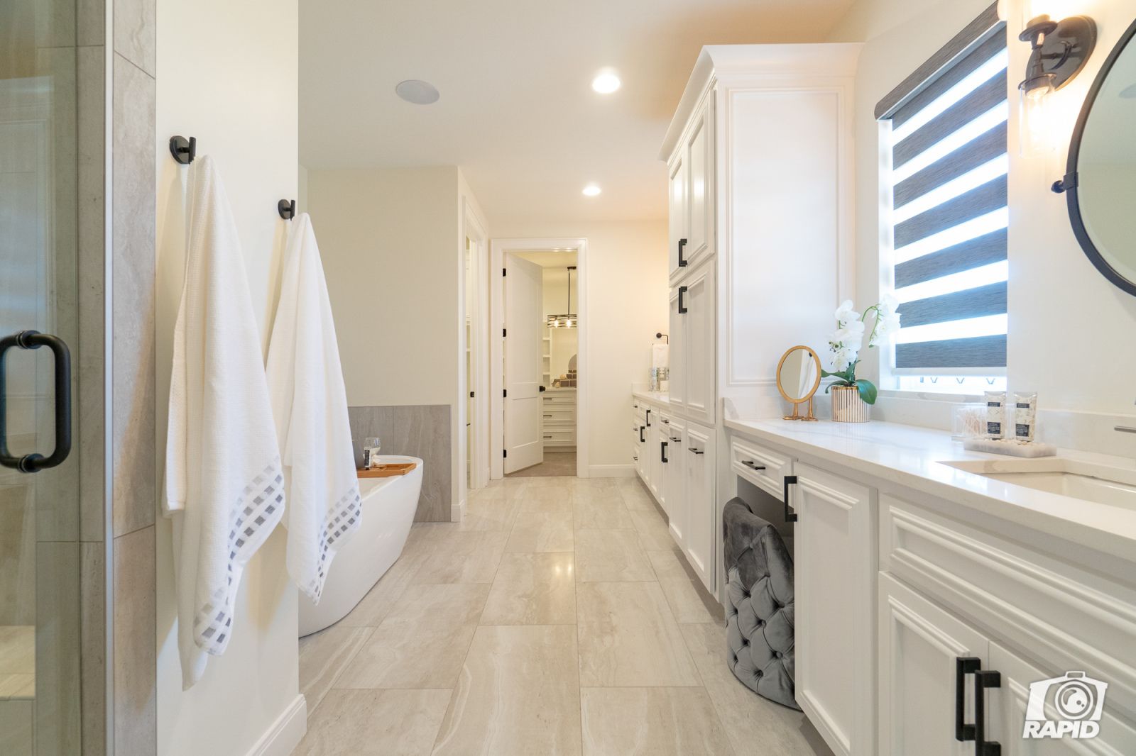 A bathroom with white cabinets and black handles