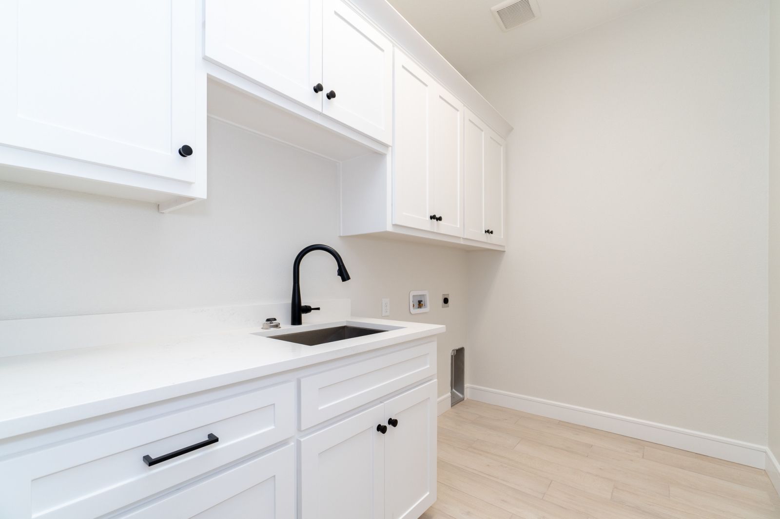 A kitchen with white cabinets and a black sink