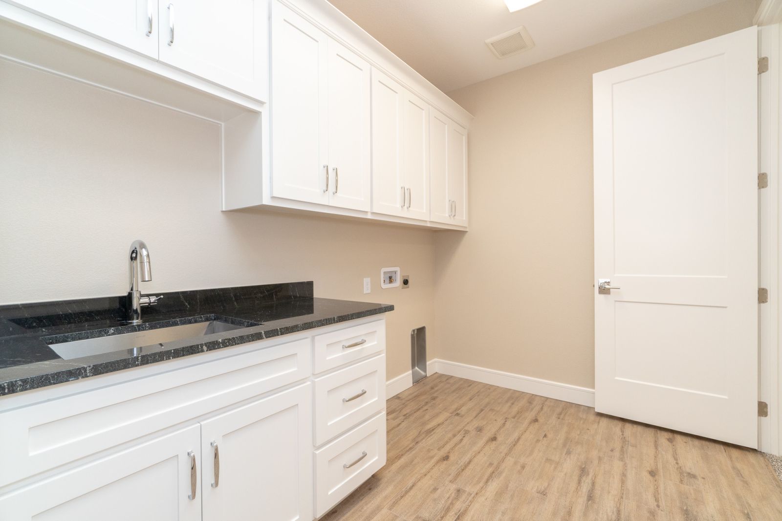 An empty kitchen with white cabinets and a sink