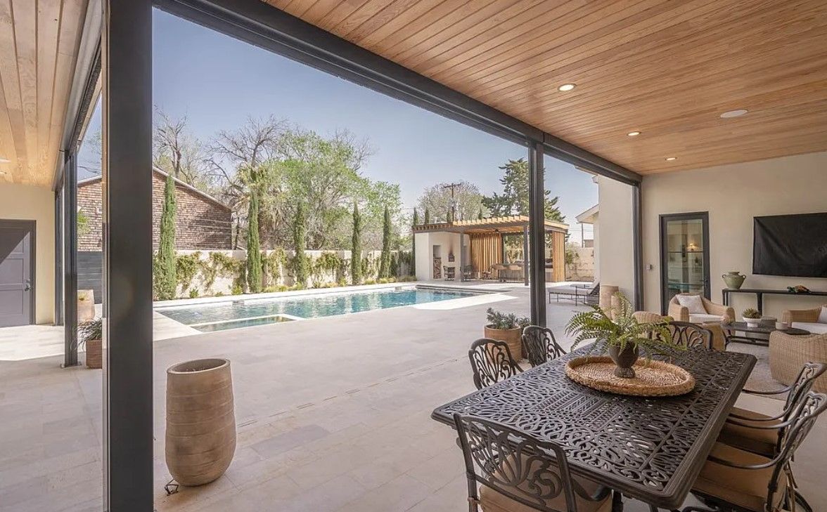 A stone house with a patio and a wooden fence in the backyard.