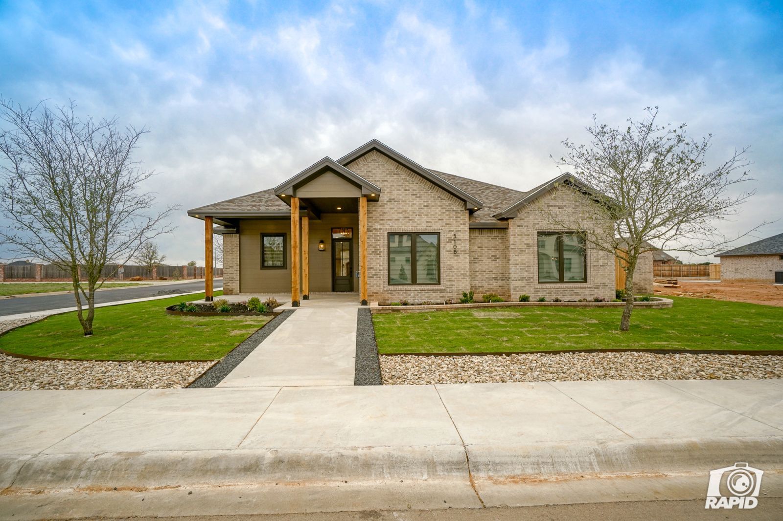 A brick house with a concrete walkway leading to it