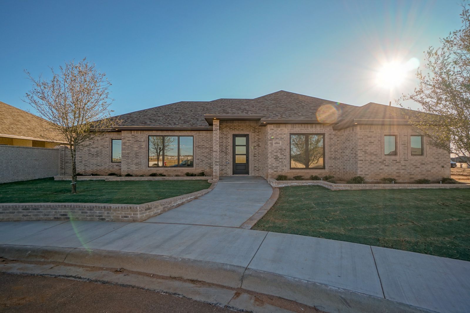 A brick house with a concrete walkway leading to it