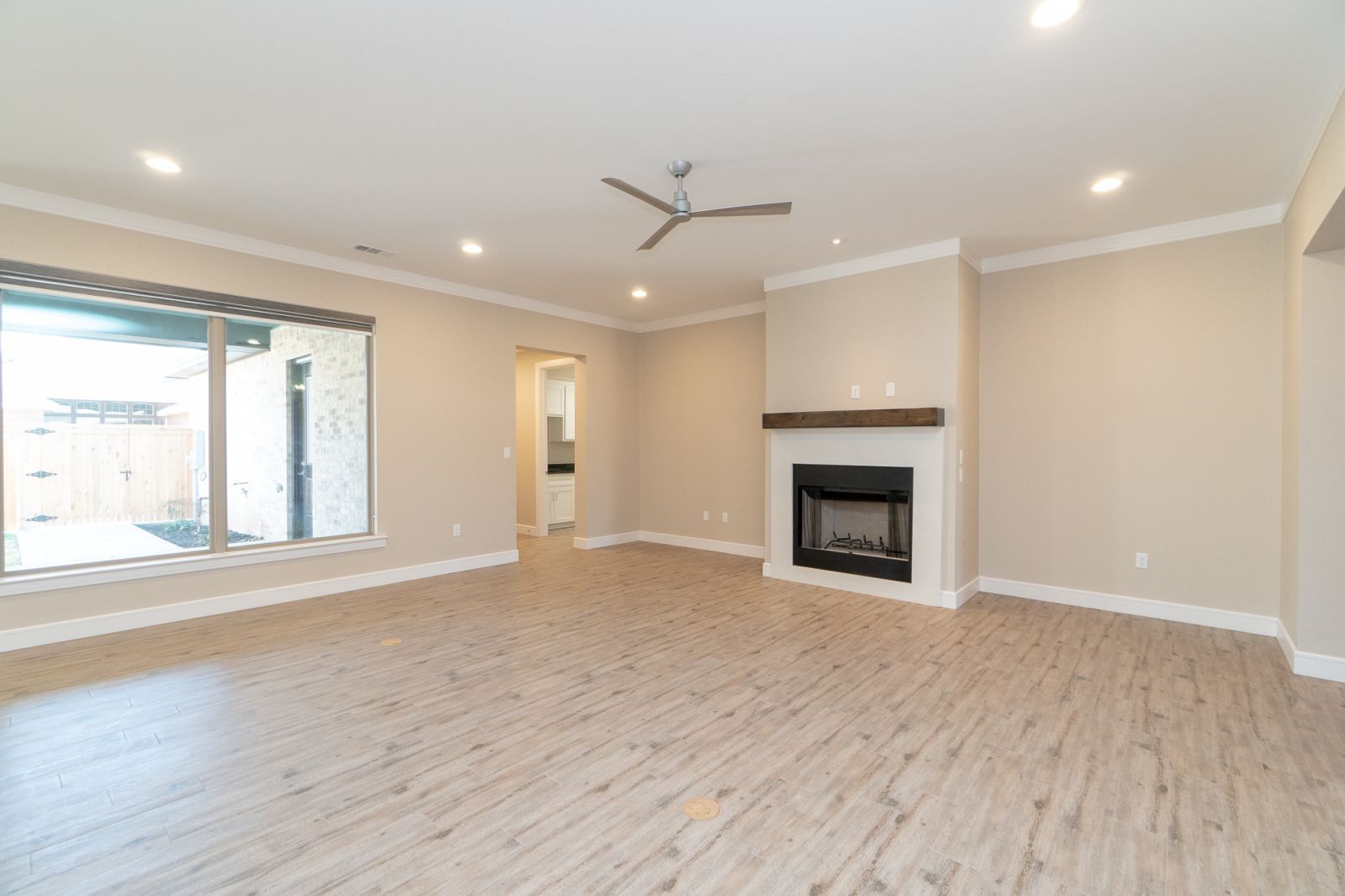 An empty living room with a fireplace and ceiling fan