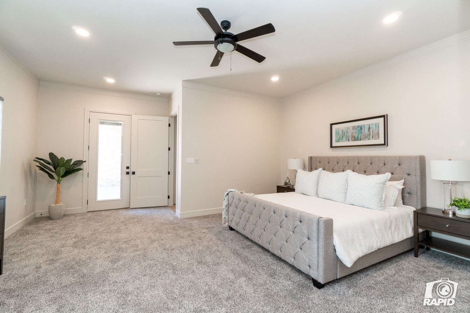 A bedroom with a large bed and a ceiling fan