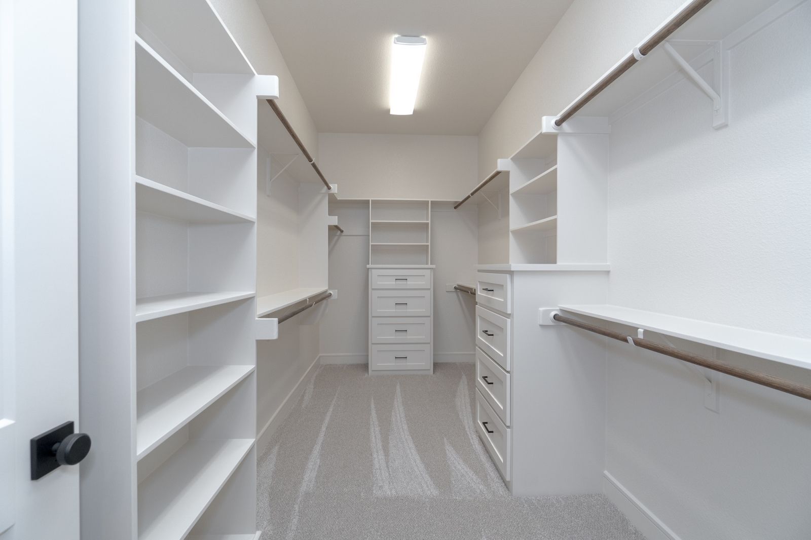 A walk in closet with lots of shelves and drawers