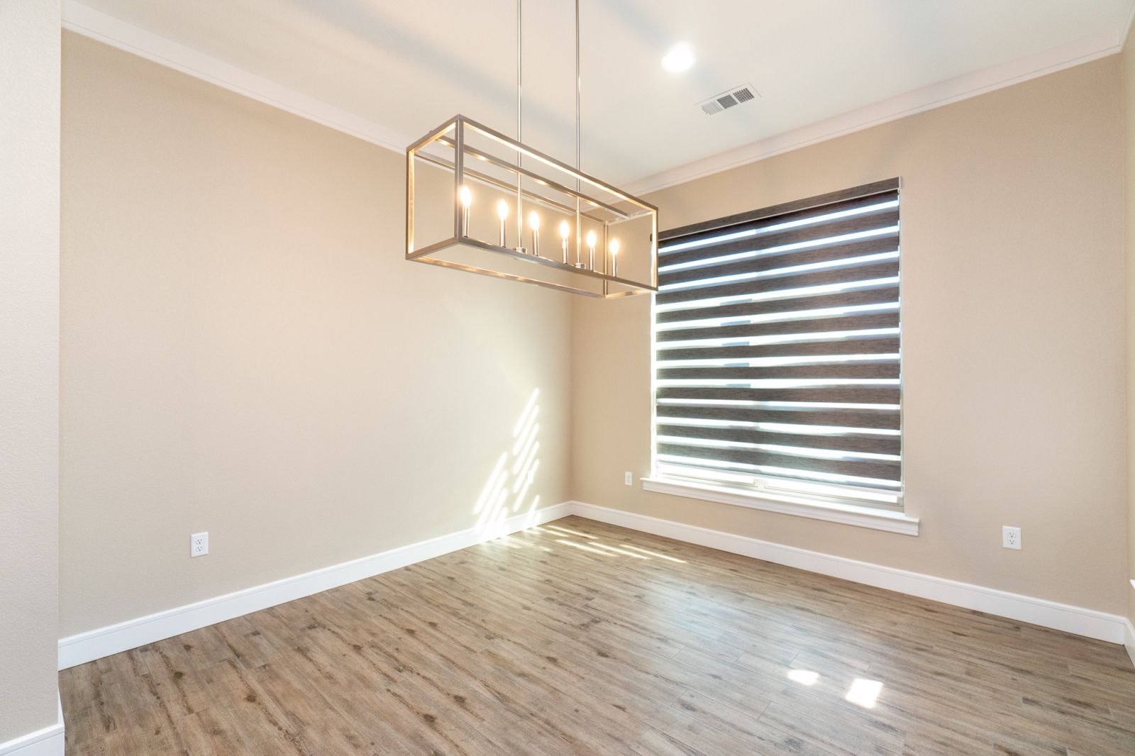 An empty room with a window and a chandelier hanging from the ceiling