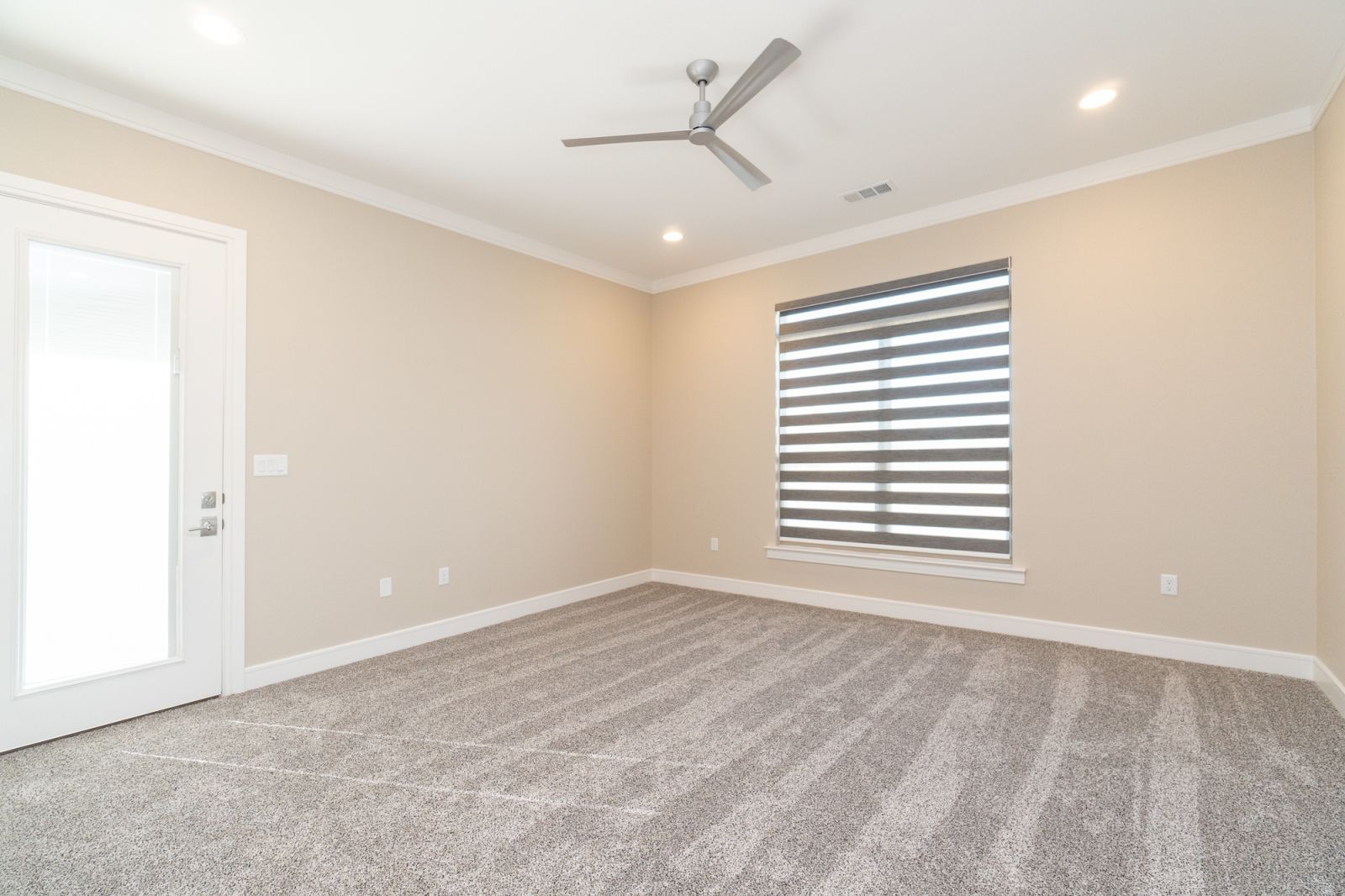 An empty bedroom with a ceiling fan and a window.