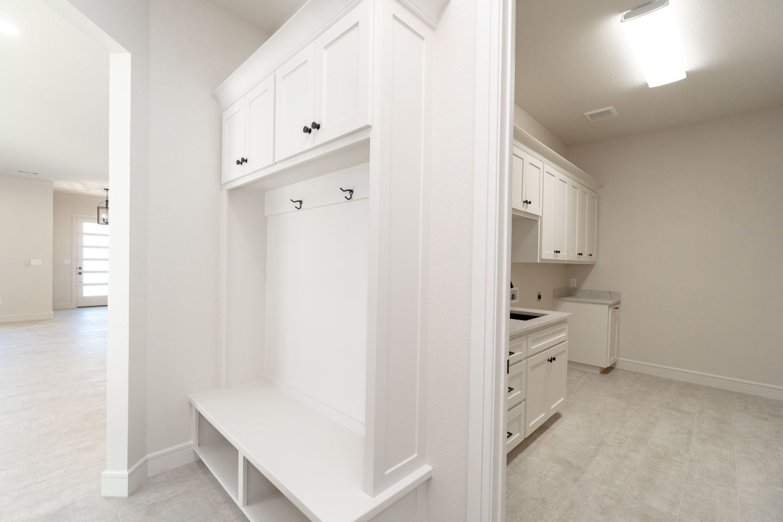 A hallway in a house with white cabinets and a bench.