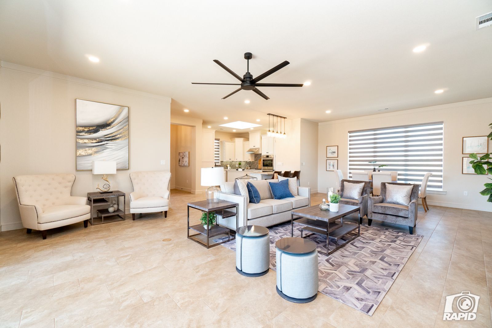 A living room with a couch and chairs and a ceiling fan