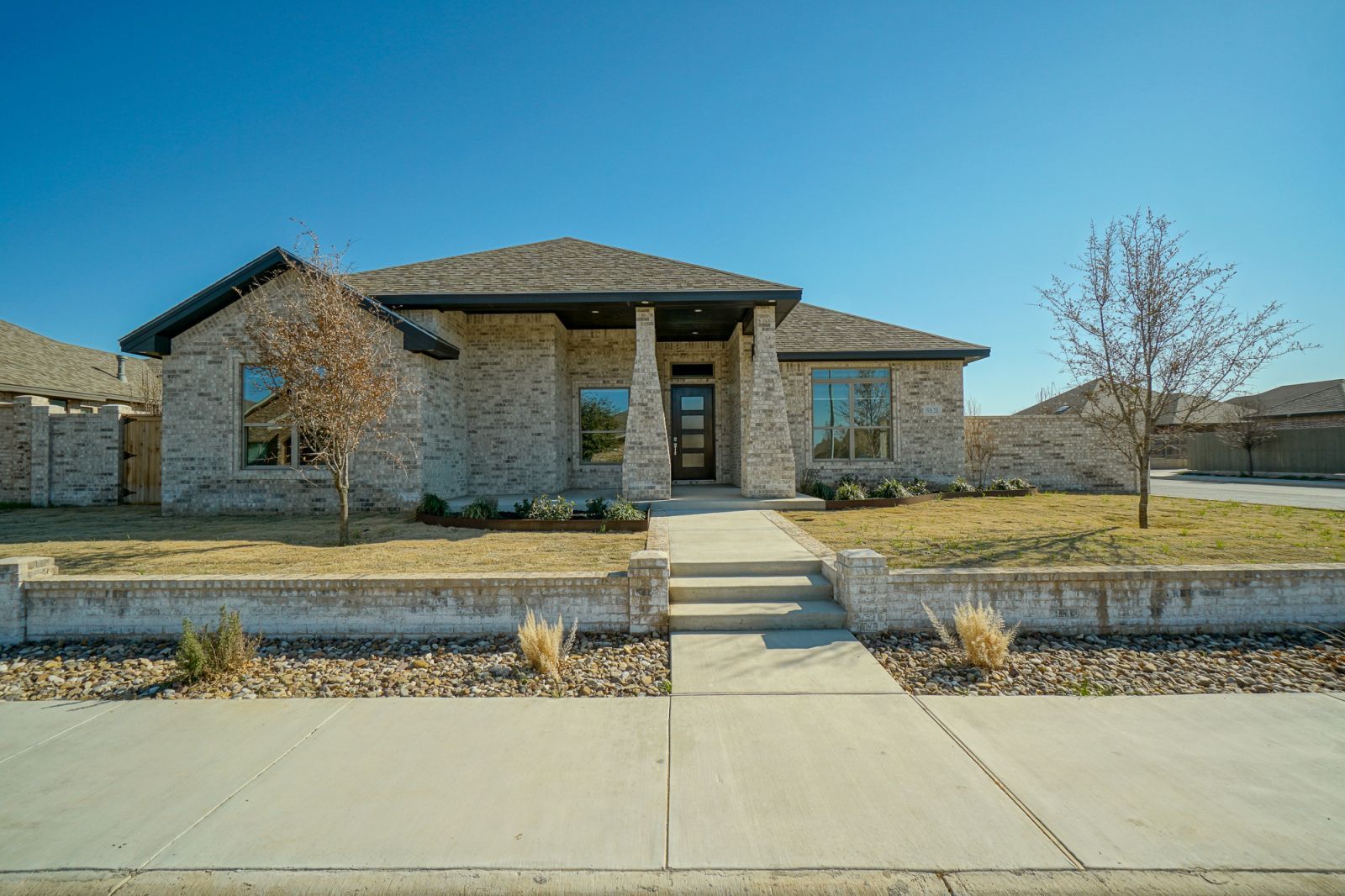 A brick house with a concrete walkway leading to it