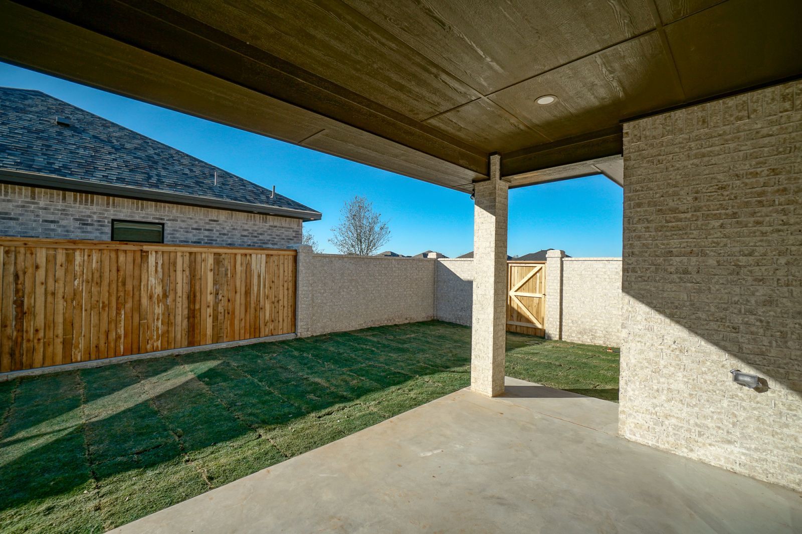 An empty backyard with a wooden fence and a house in the background