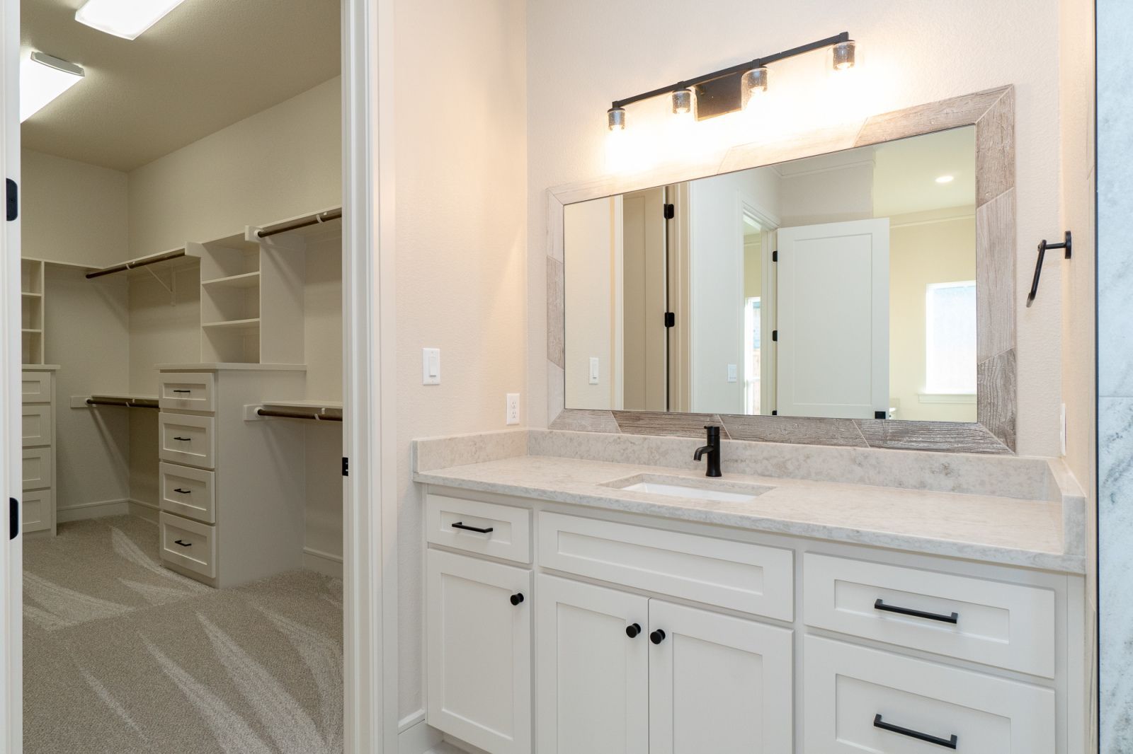 A bathroom with white cabinets and a large mirror