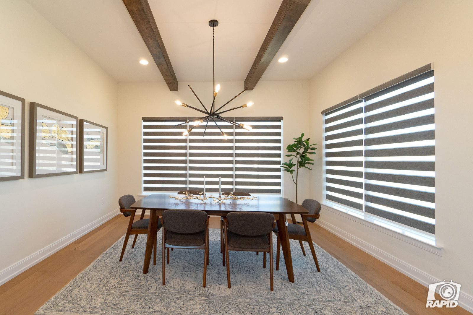 A dining room with a table and chairs and striped blinds