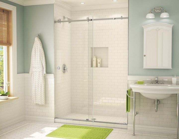 Bathroom with a white tiled shower, glass doors, and a green rug. A sink and mirror are visible.