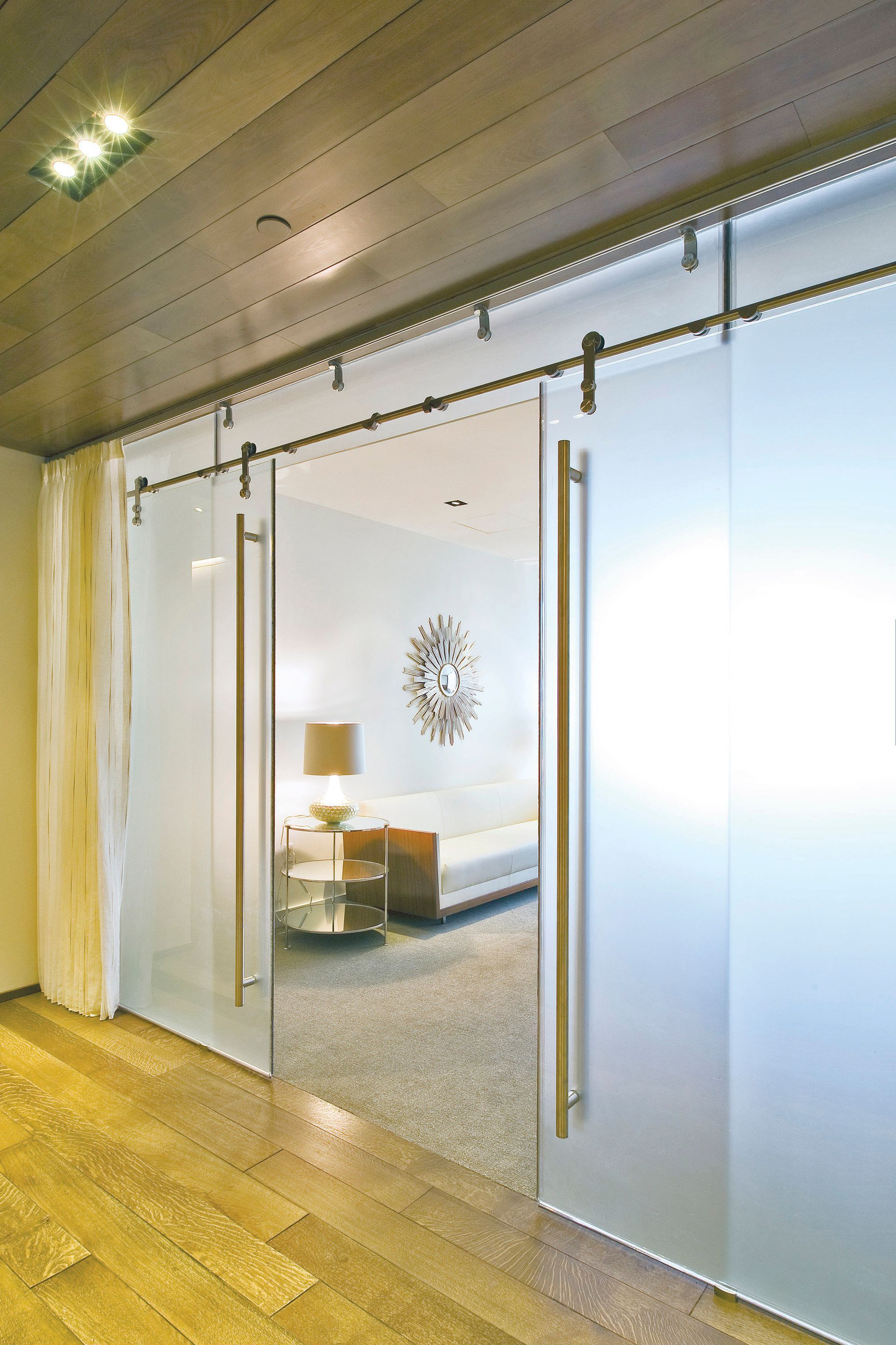Frosted glass sliding doors leading to a bedroom with a neutral color palette.