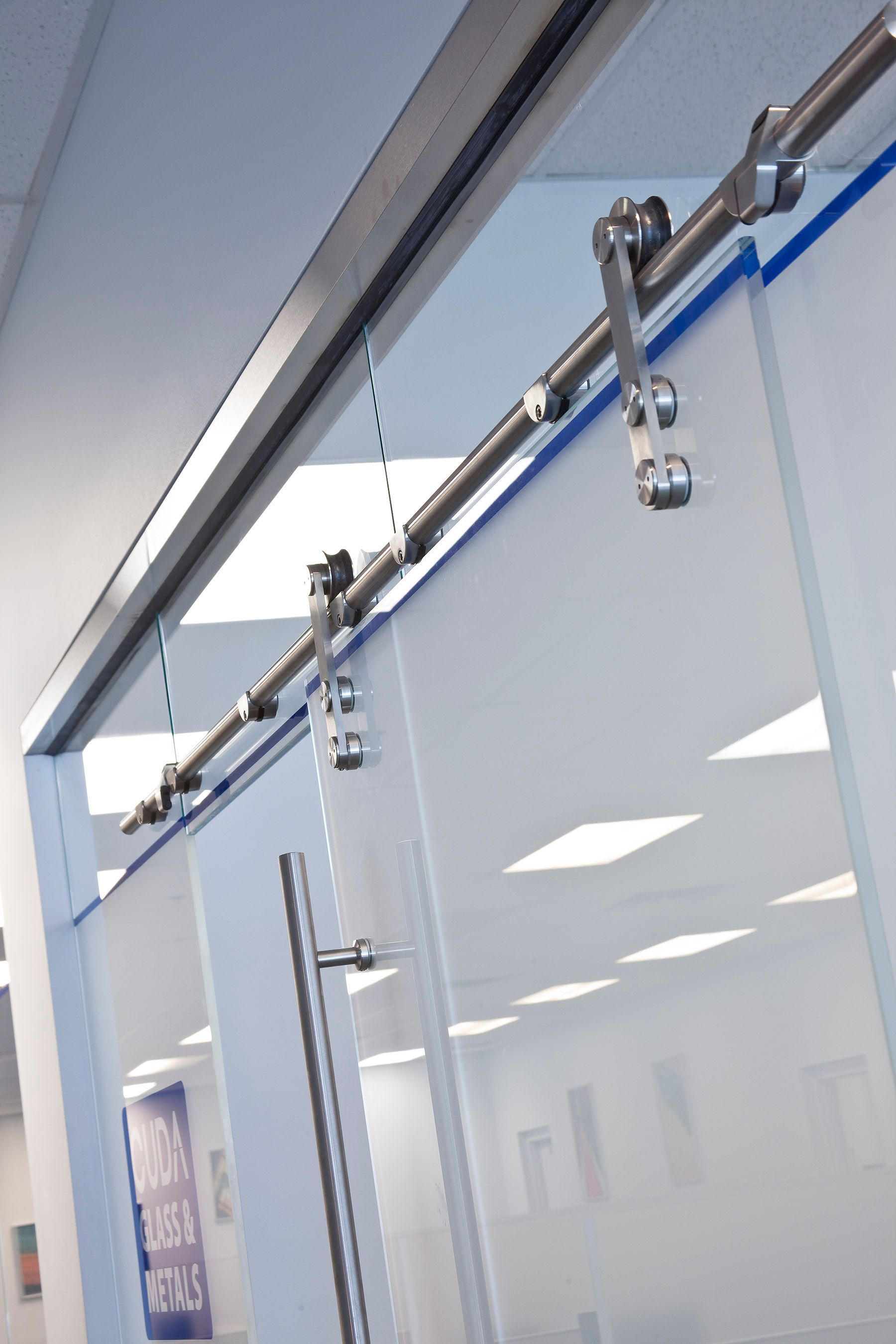 Sliding glass door with metal track and rollers, indoor setting.